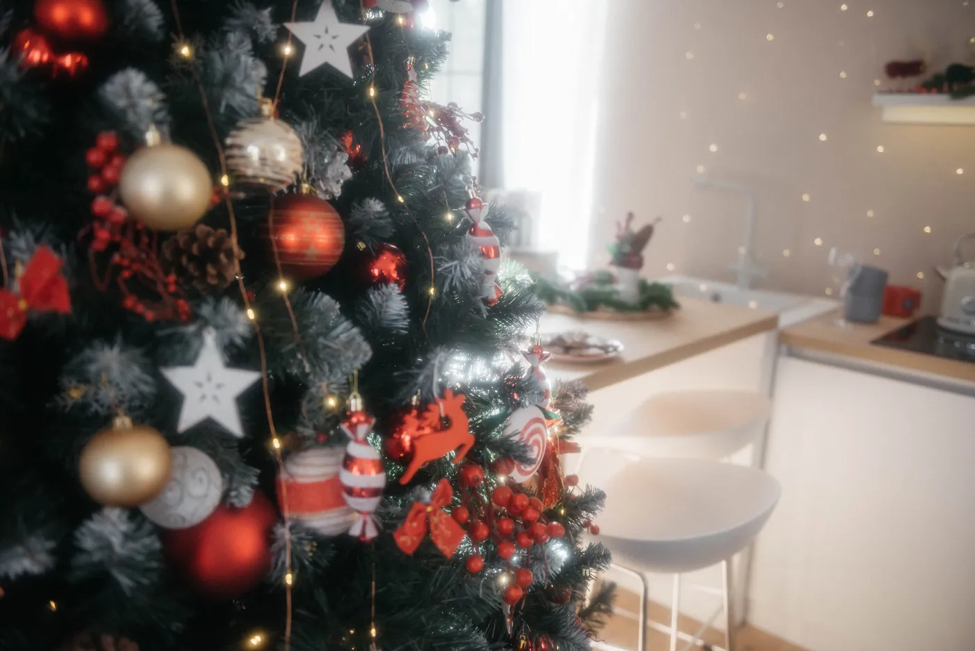 A decorated Christmas tree with baubles and lights in a cozy kitchen.
