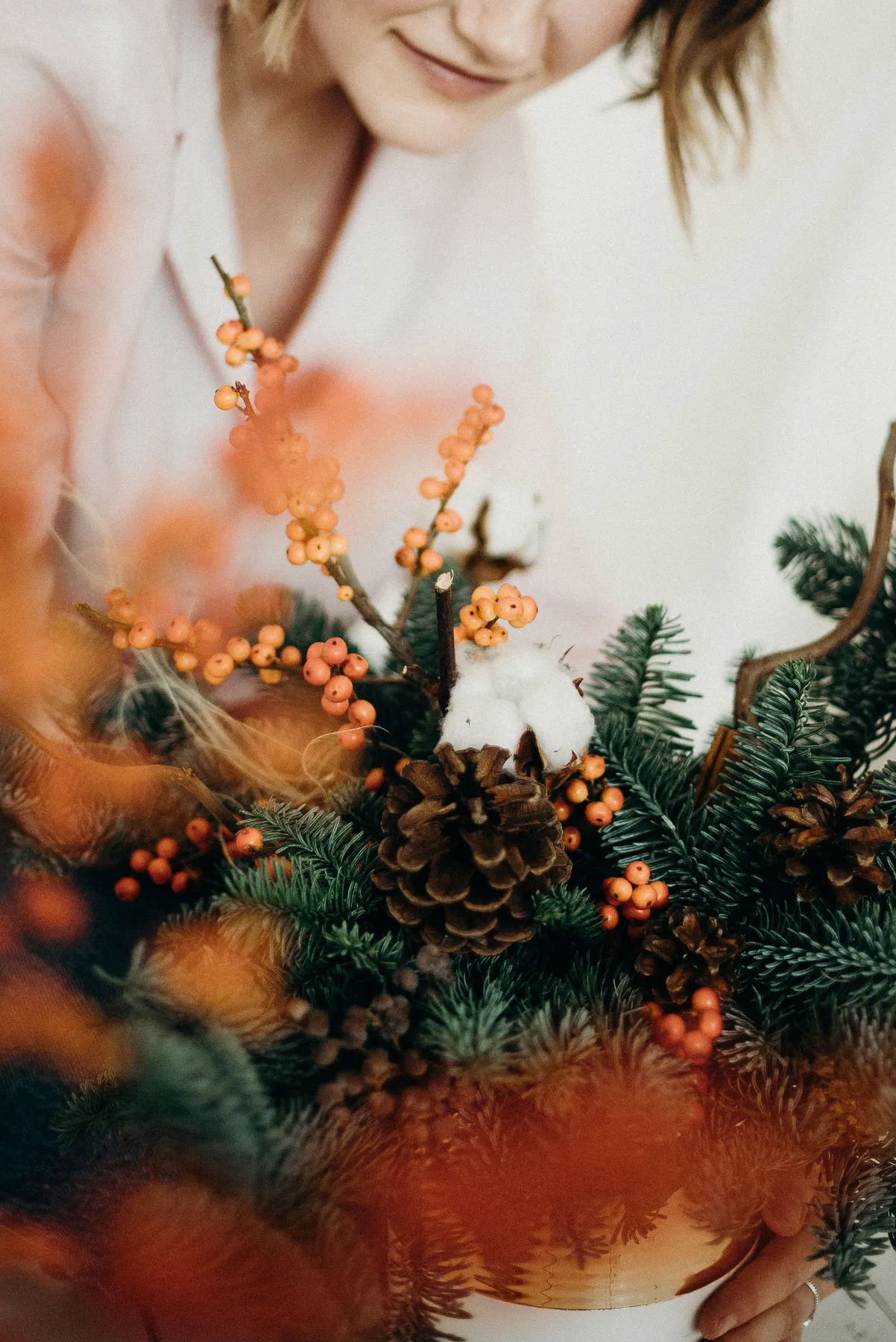 A detailed close-up of a festive Christmas floral arrangement with pine cones and berries.