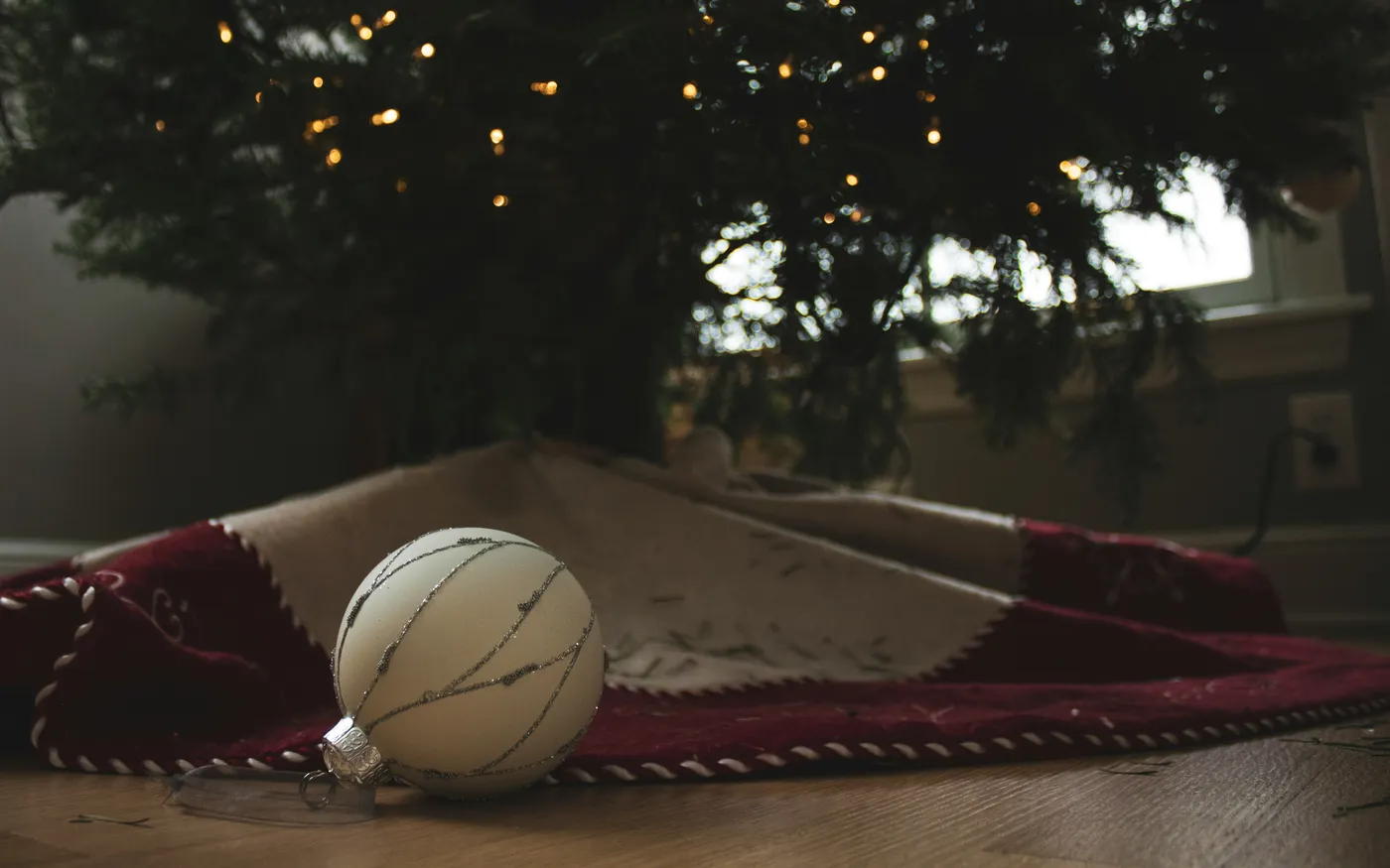 a fallen white ornament on the ground in front of a christmas tree