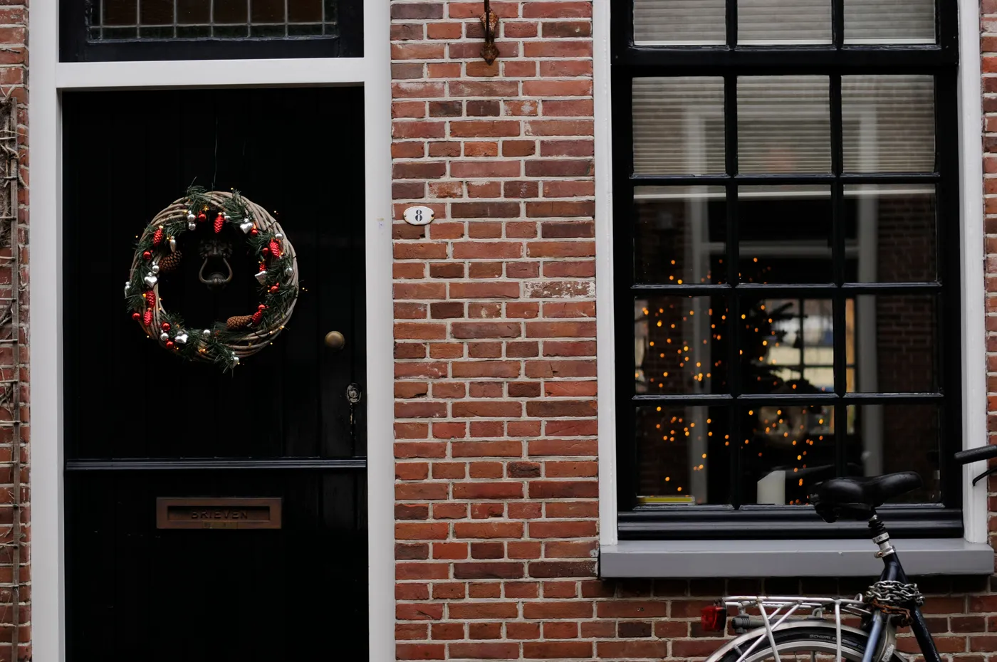 A festive brick house in Edam, Netherlands, featuring a Christmas wreath on the door and a bicycle parked outside.