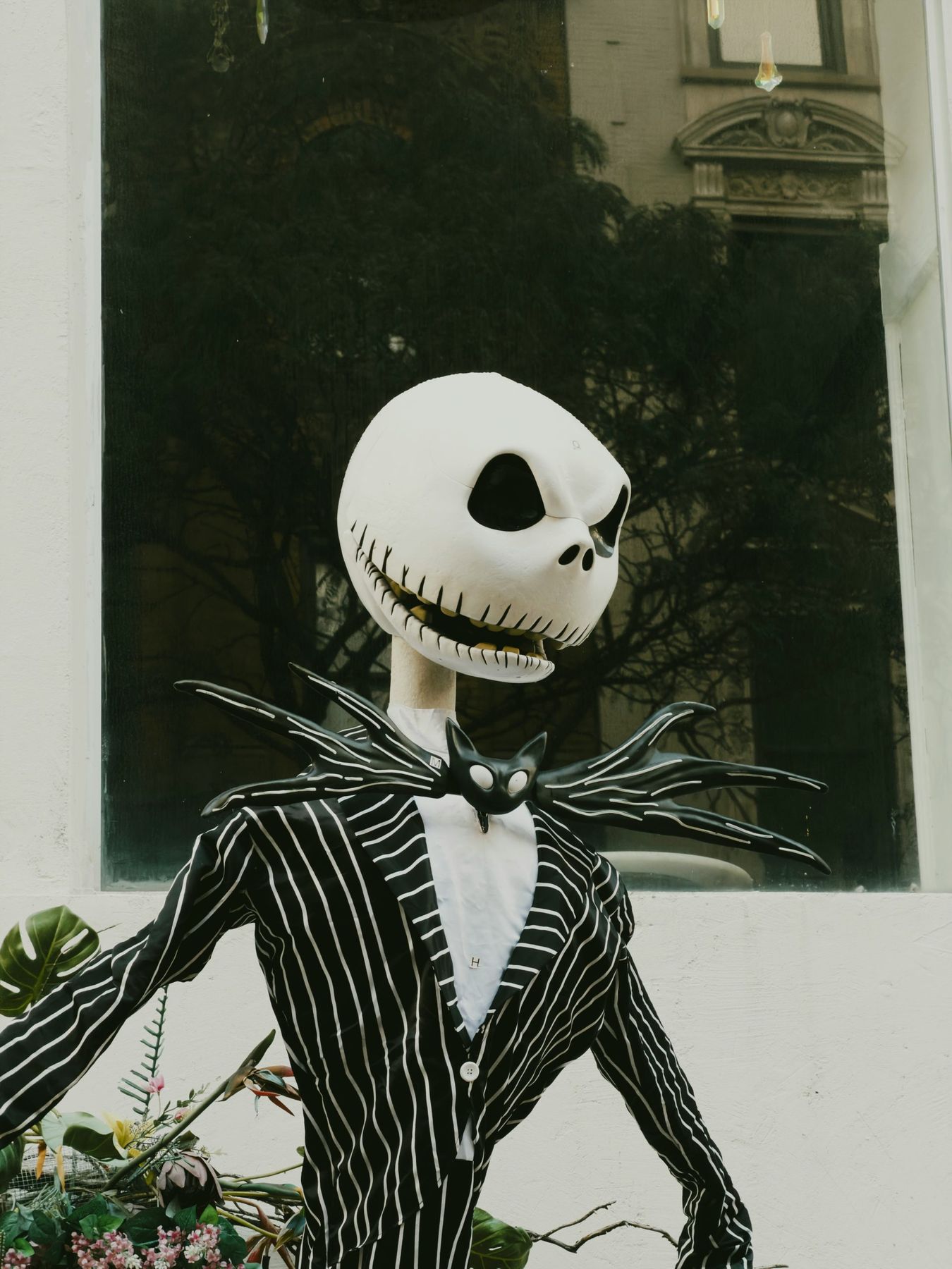 A Jack Skellington figure in a pinstriped suit standing before a window