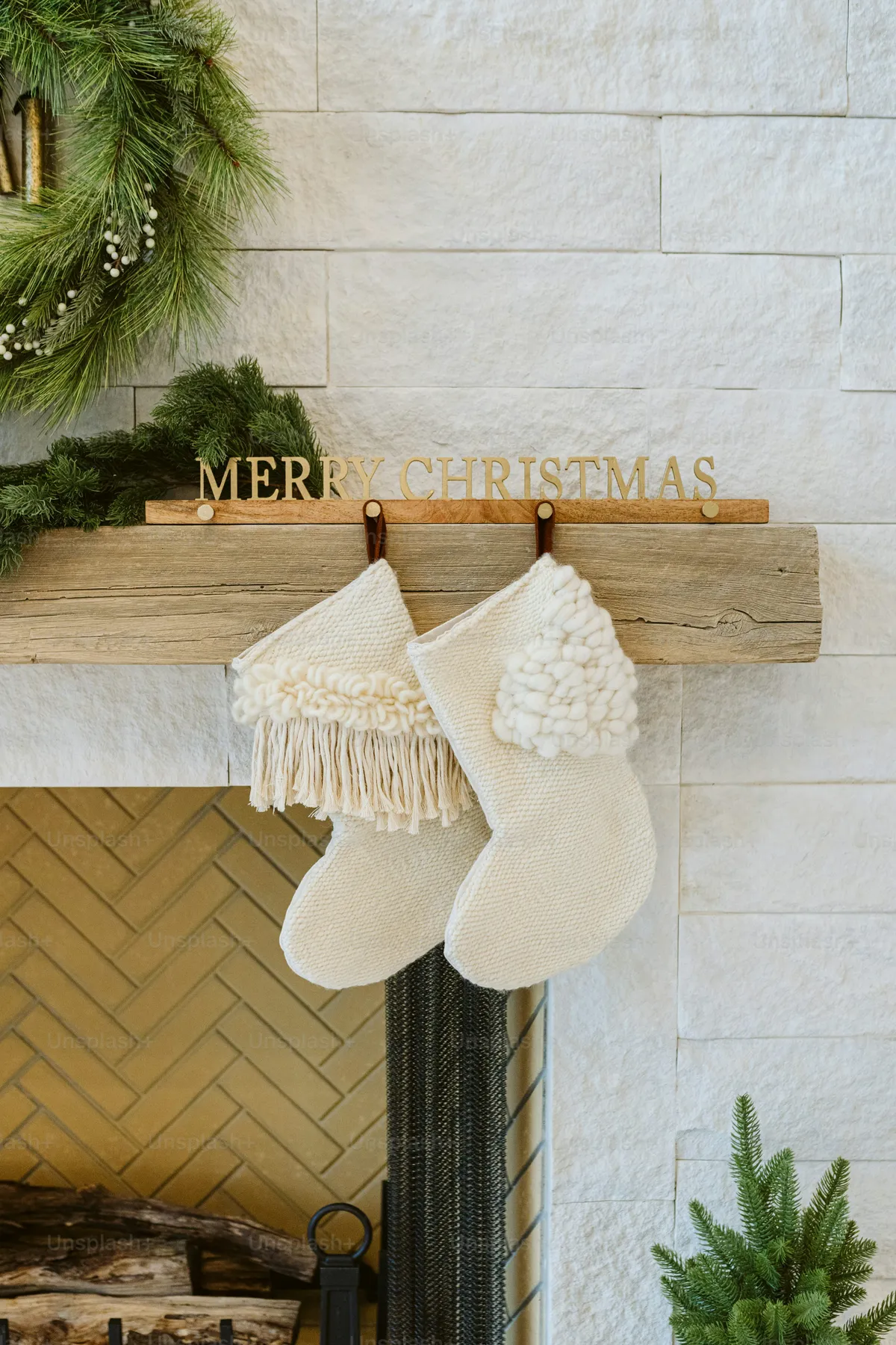 A person hanging stockings on a fireplace with a merry christmas sign -  Photo on Unsplash+