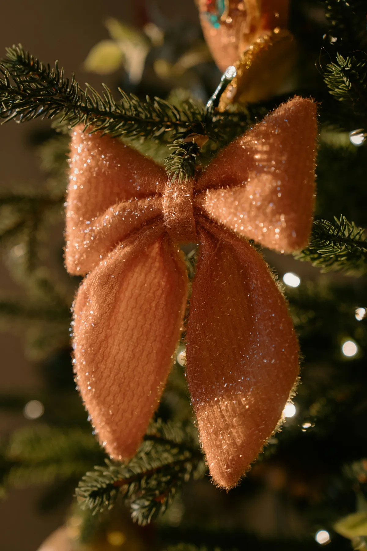 A sparkly peach bow adorns a christmas tree