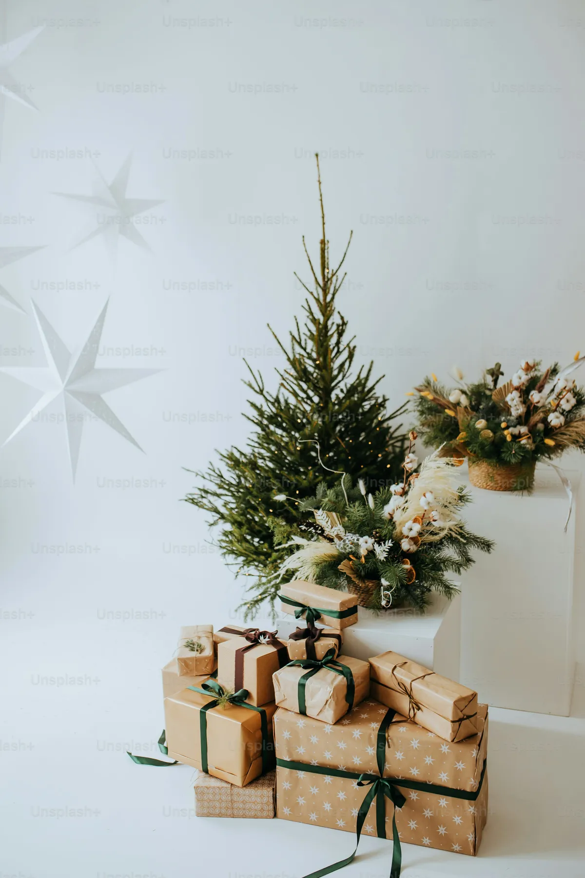 A white christmas tree with presents under it - Photo on Unsplash+