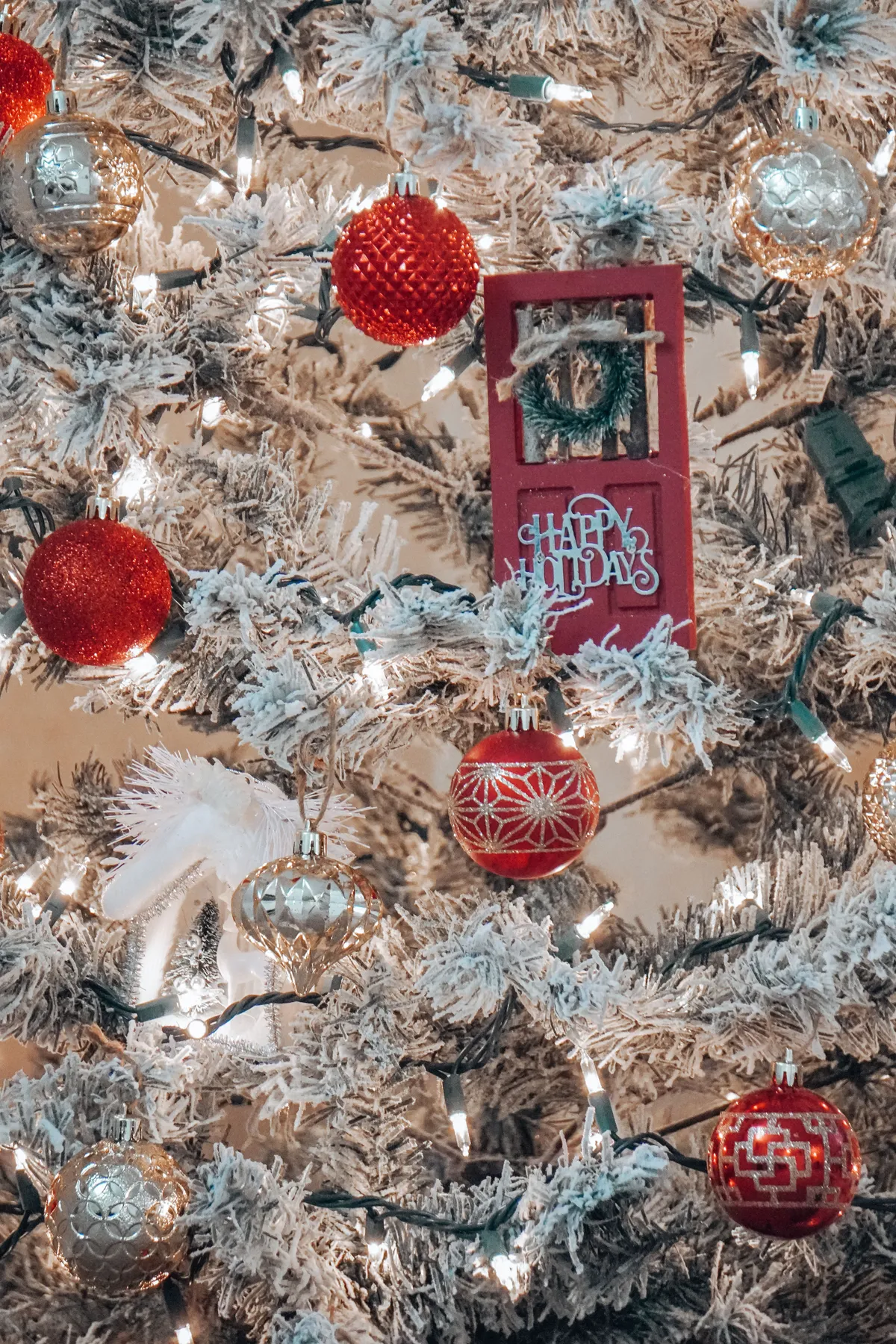 Beautifully decorated Christmas tree with red, gold, and silver ornaments and glowing lights.