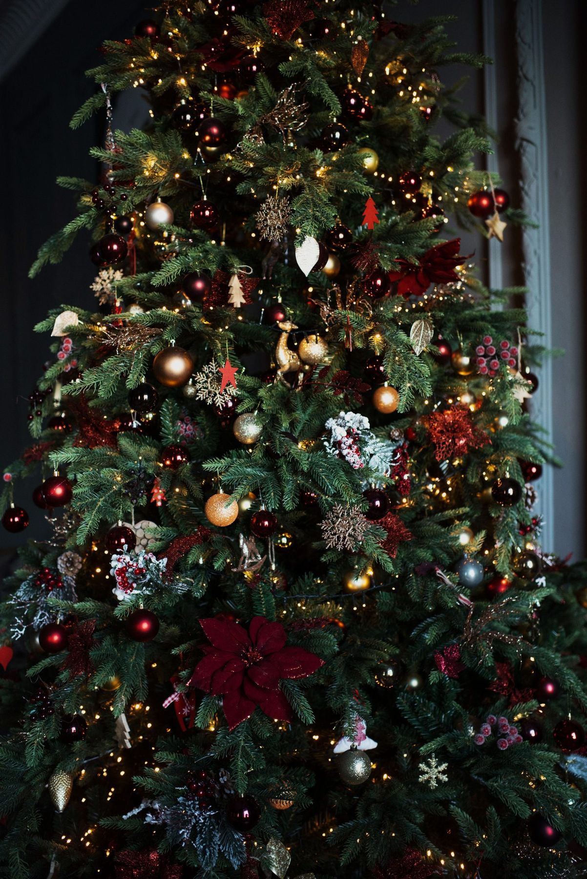 Beautifully decorated Christmas tree with glowing lights and festive ornaments indoors.