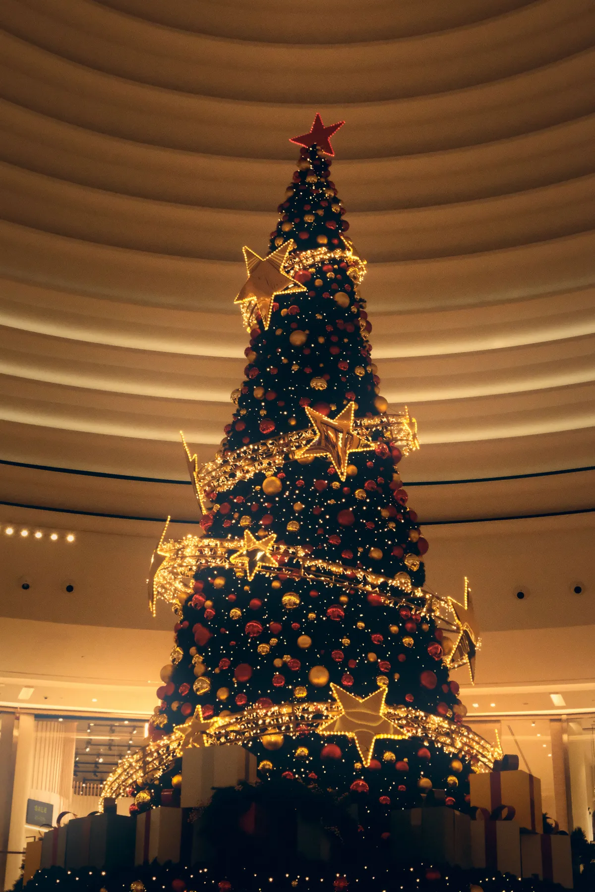 Captivating view of a lavishly decorated Christmas tree adorned with golden stars in a bustling mall.