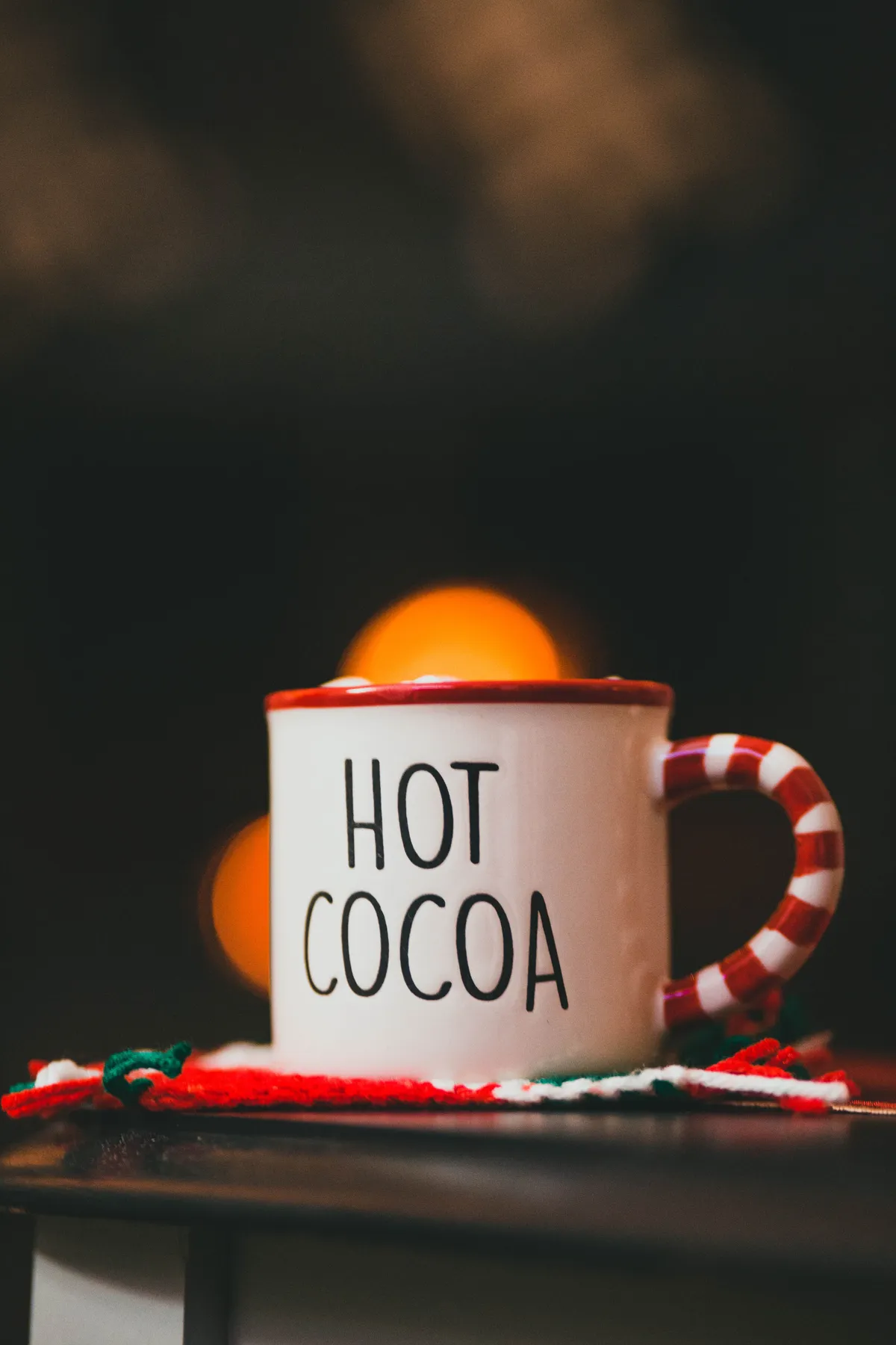 Ceramic mug of hot cocoa with festive decor, perfect for winter coziness.