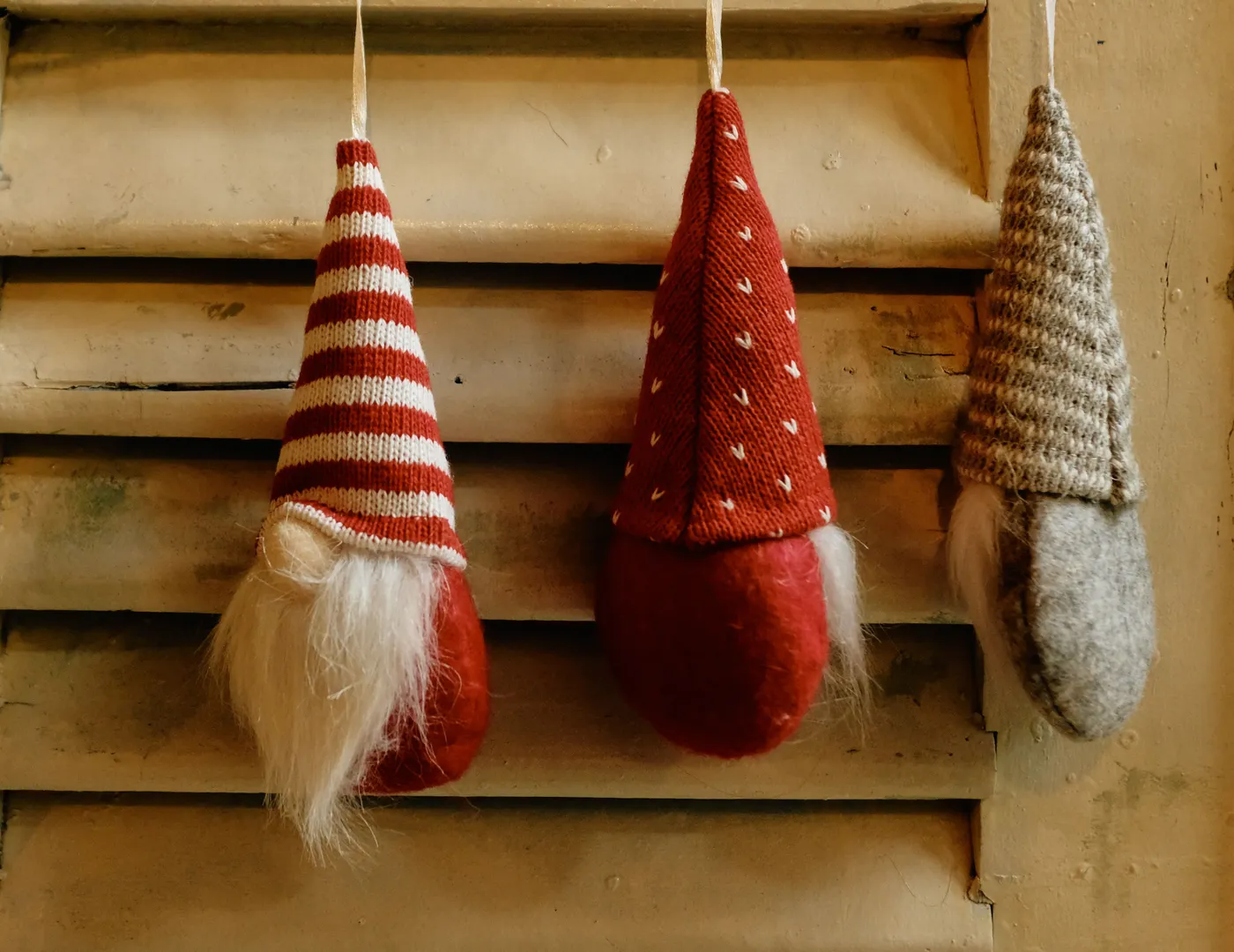 Charming gnome ornaments hang on a rustic wooden shutter, adding festive cheer.