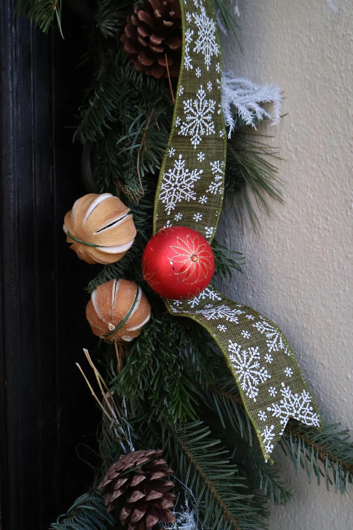 Christmas wreath with ornaments, pinecones, and ribbon