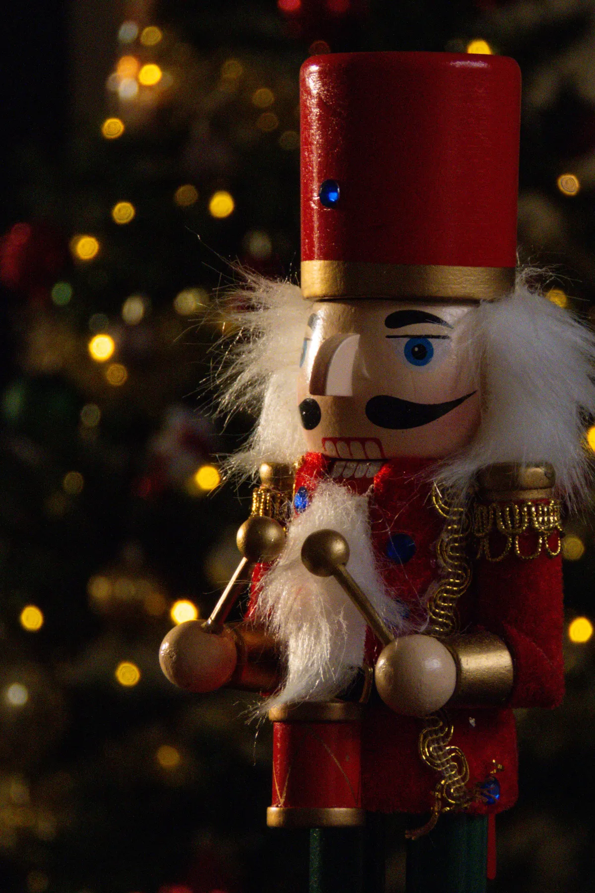 Classic nutcracker soldier in front of a festive Christmas tree with bokeh lights.