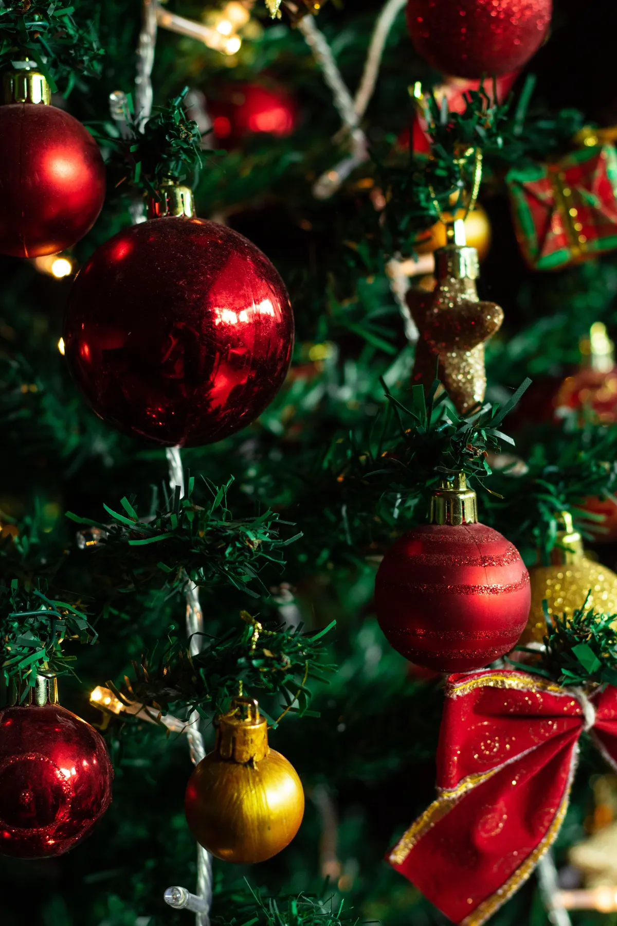Close-up of a Christmas tree adorned with red baubles and decorative lights.