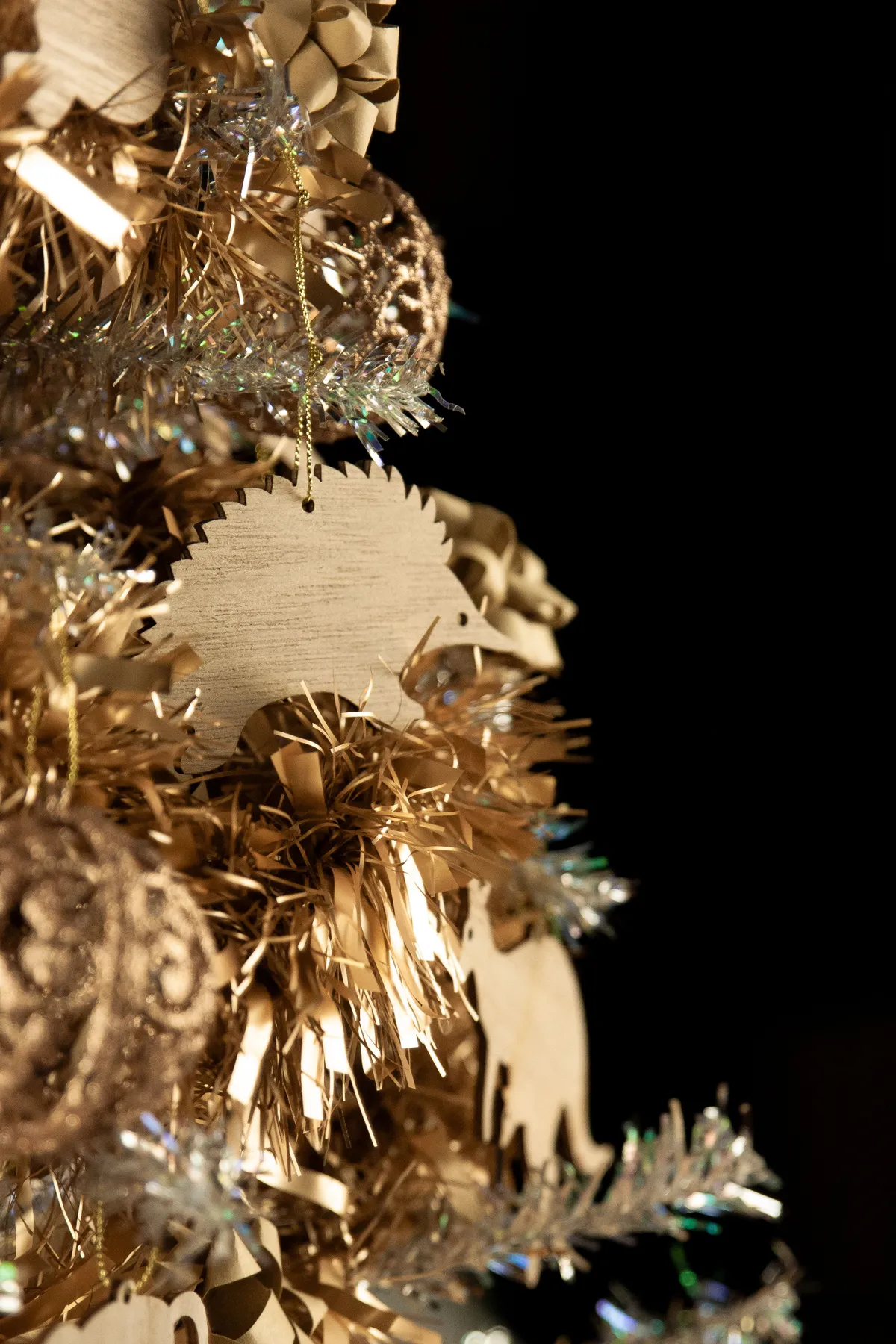 Close-up of festive gold ornaments and tinsel on a Christmas tree.