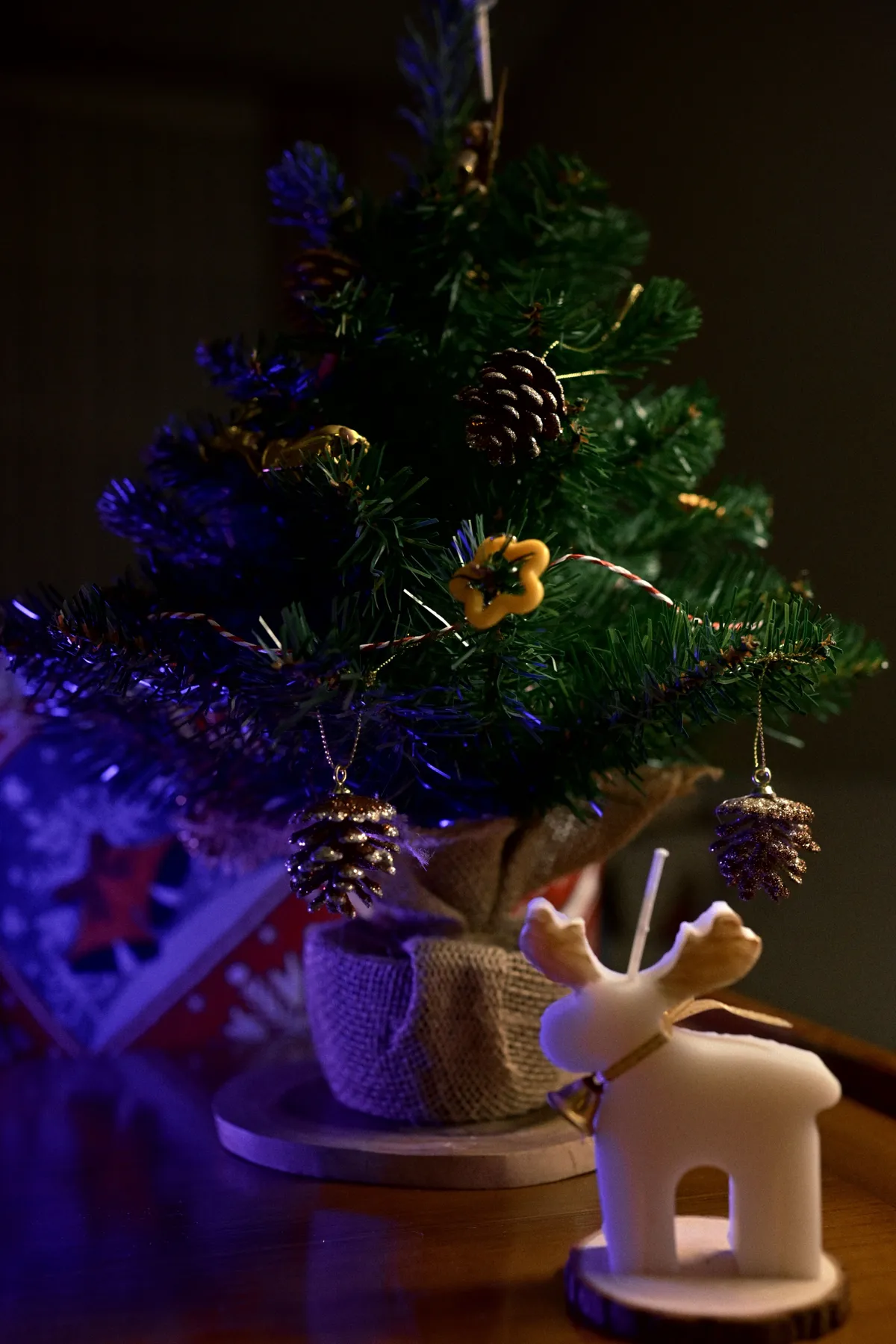Cozy holiday scene with a small decorated tree and candle holder deer ornament.