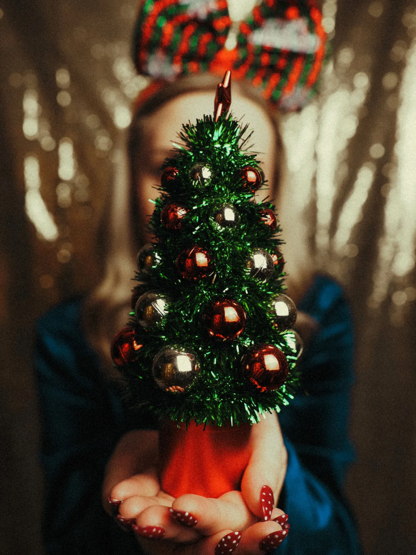 Cozy holiday scene with a woman holding a mini decorated Christmas tree.