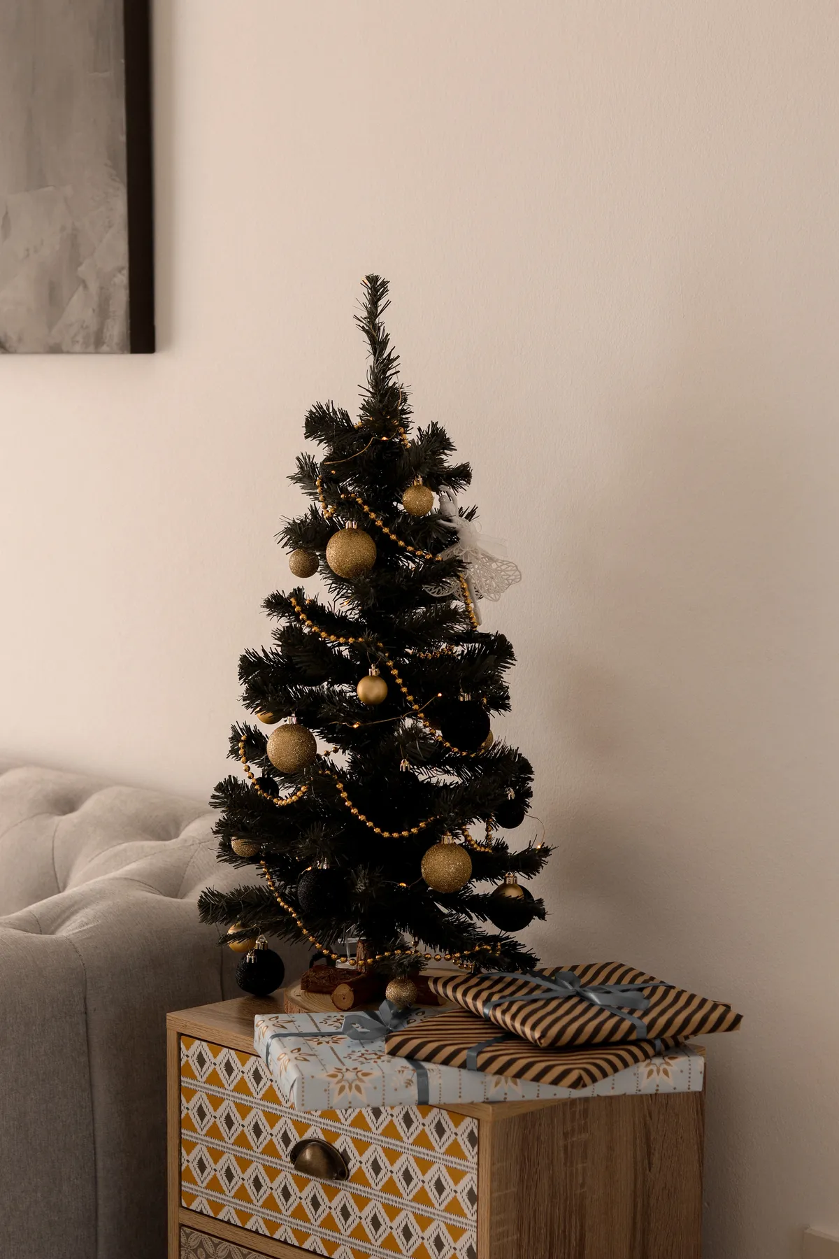 Elegant Christmas tree with decorations and gifts on a cabinet, perfect for holiday ambiance.