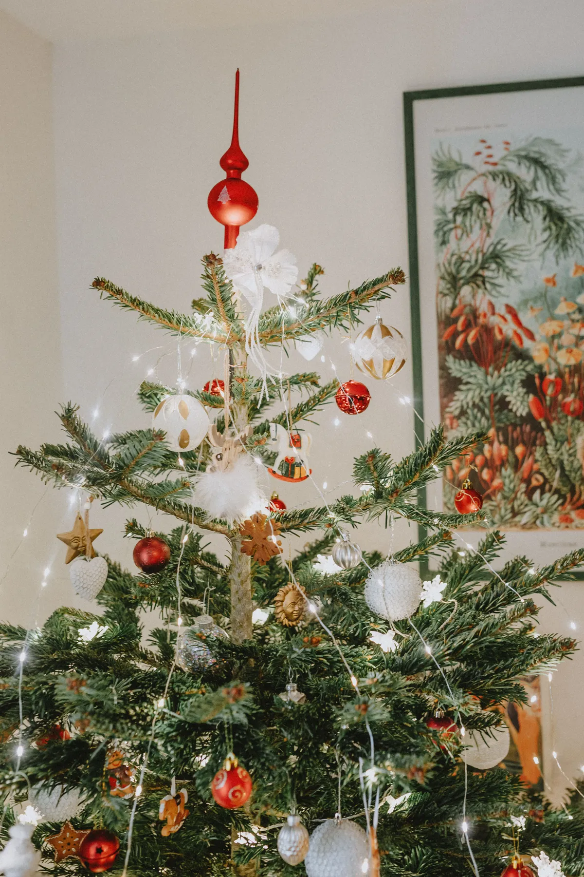 Festive Christmas tree adorned with ornaments and lights inside a cozy home.