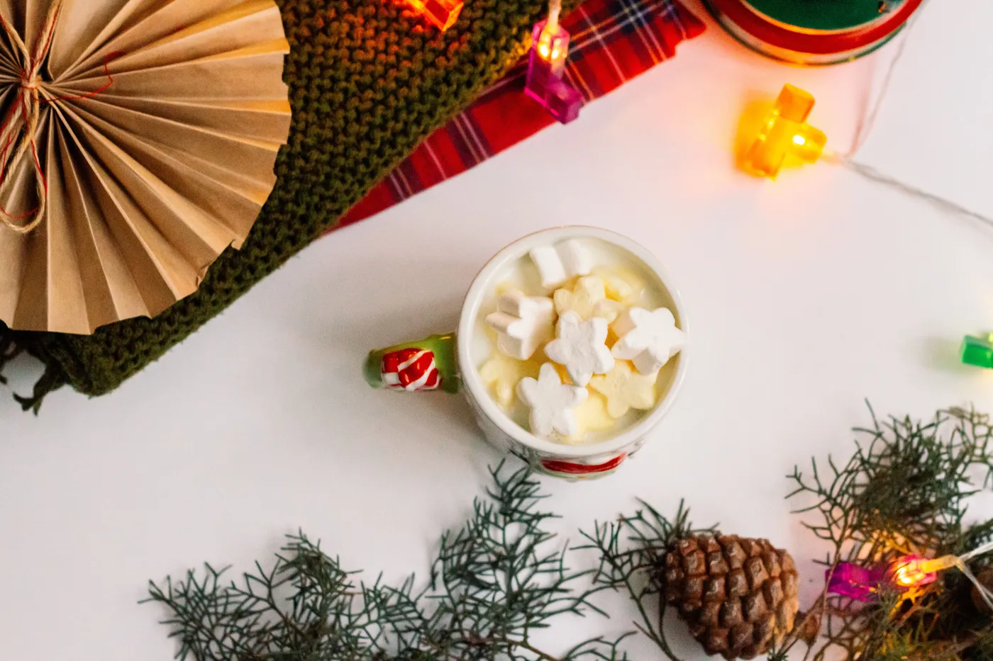 Festive hot chocolate with marshmallows, pinecones, and holiday lights for a cozy winter vibe.
