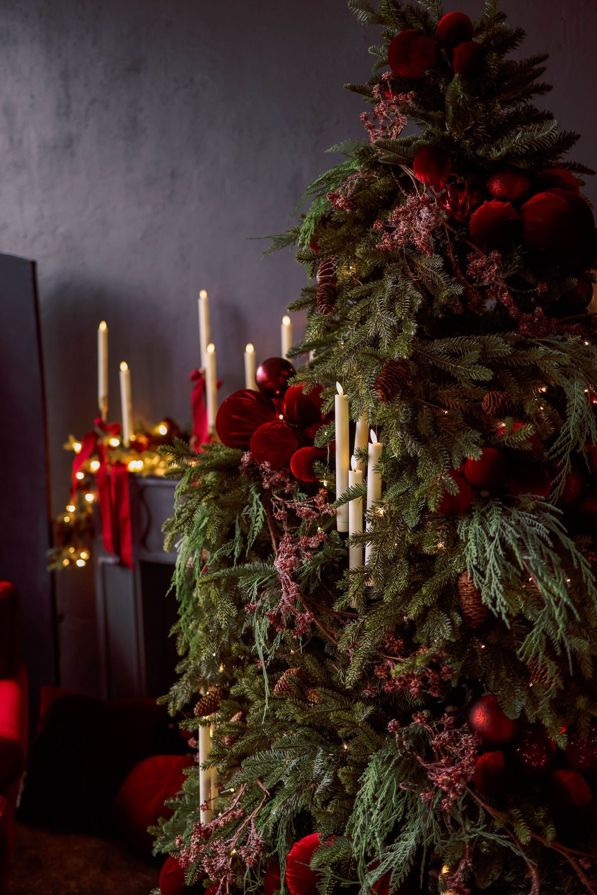 Luxurious Christmas tree adorned with red ornaments and candles, creating a festive ambiance.