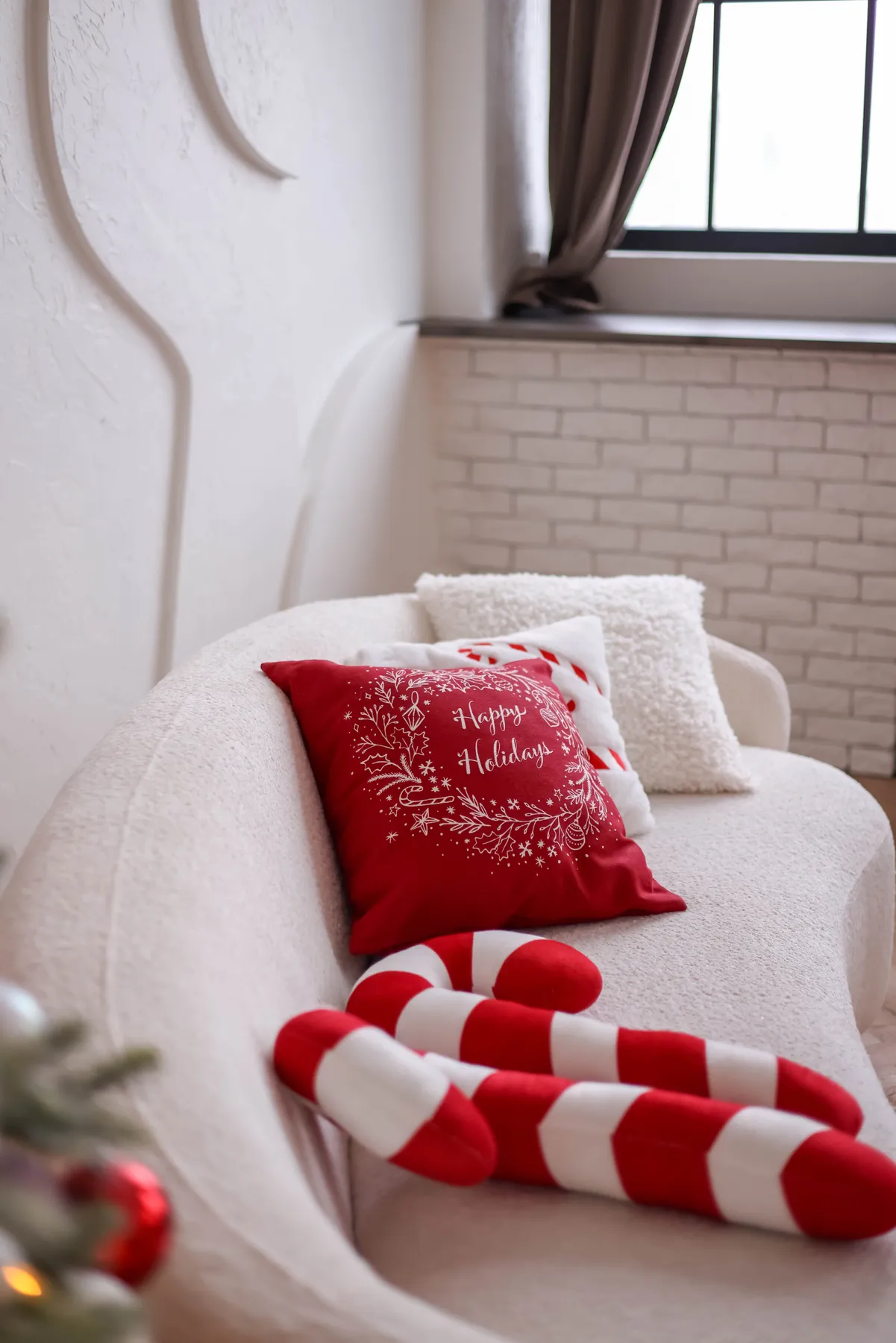 Modern living room with festive Christmas decor and cozy pillows on a white sofa.