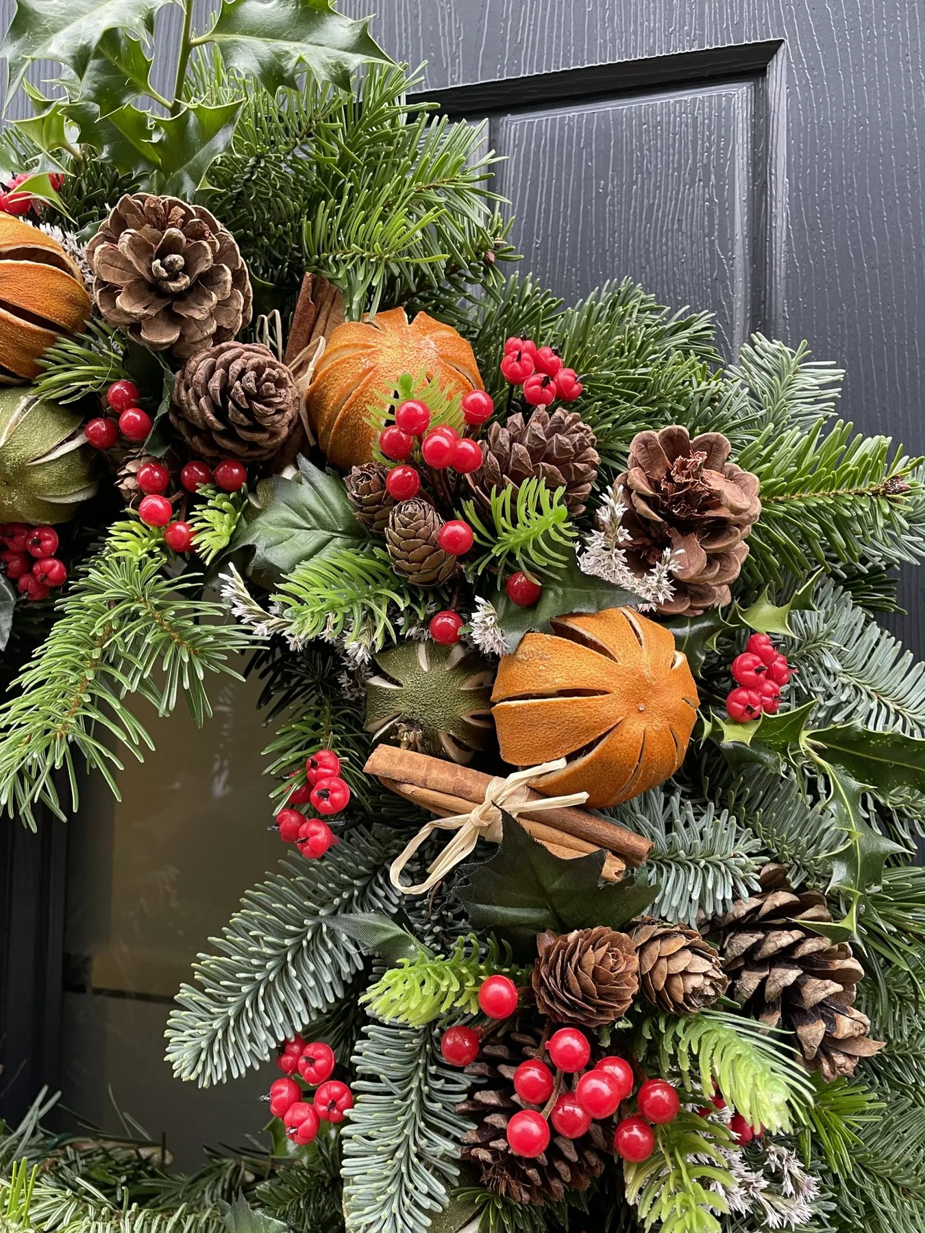 Real Handmade Christmas Wreath with foliage, holly, cones, cinnamon sticks,  dried limes and oranges, berries and hessian bow.