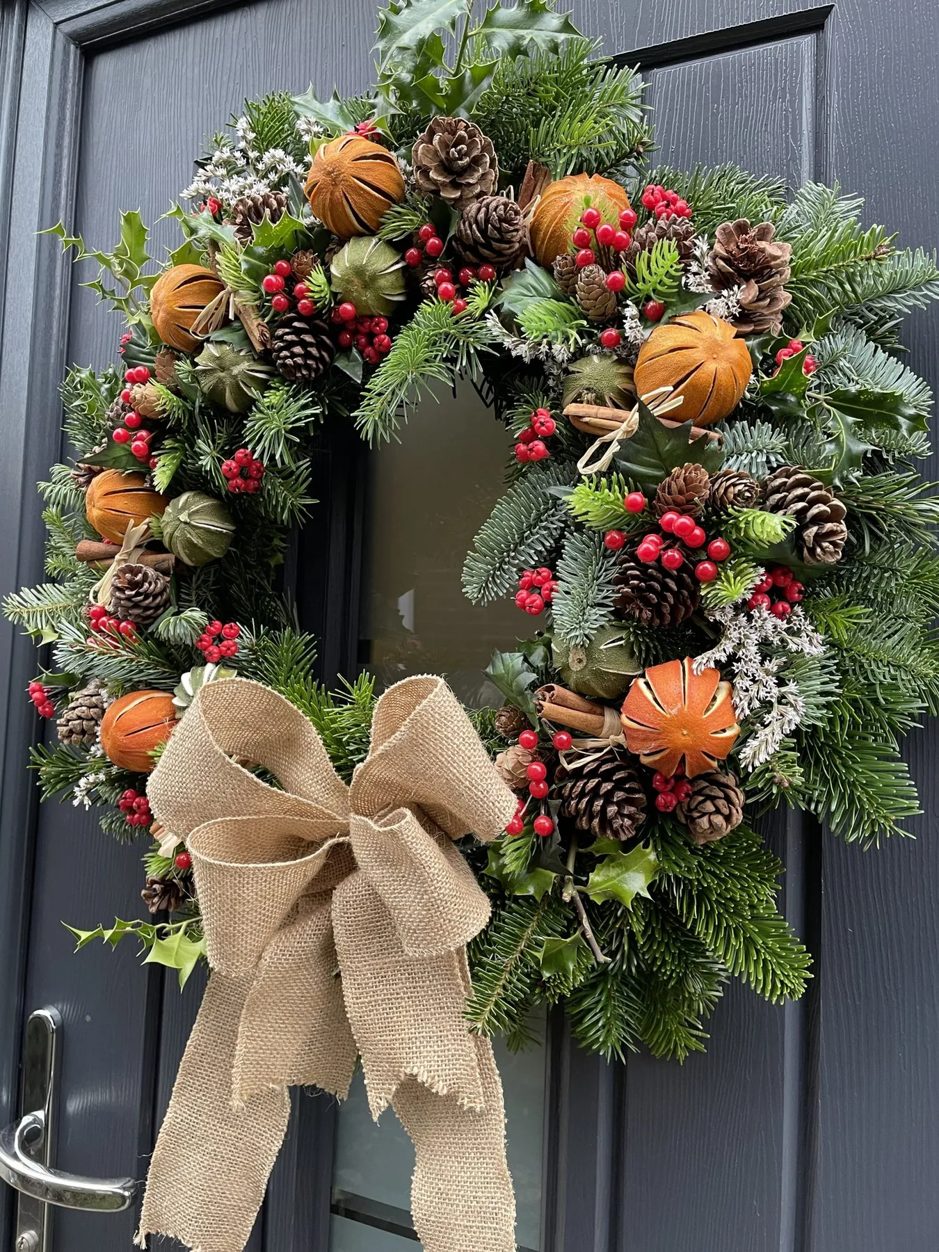 Real Handmade Christmas Wreath with foliage, holly, cones, cinnamon sticks,  dried limes and oranges, berries and hessian bow.