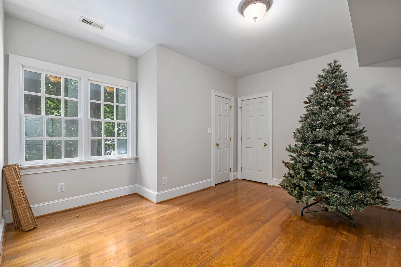 Spacious indoor room featuring frosted Christmas tree and wooden flooring, ideal for interior design inspiration.
