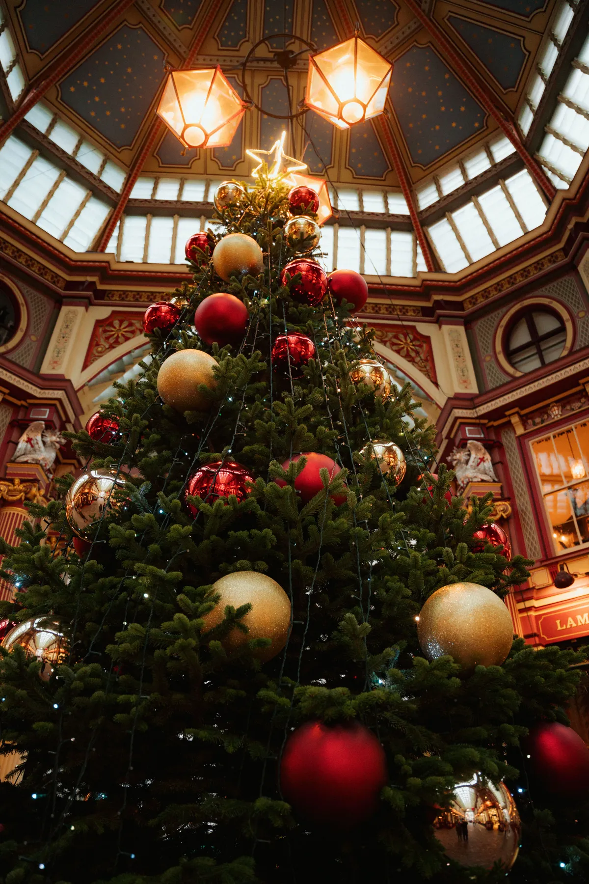 Stunning Christmas tree decked with red and gold ornaments in a festive indoor hall.
