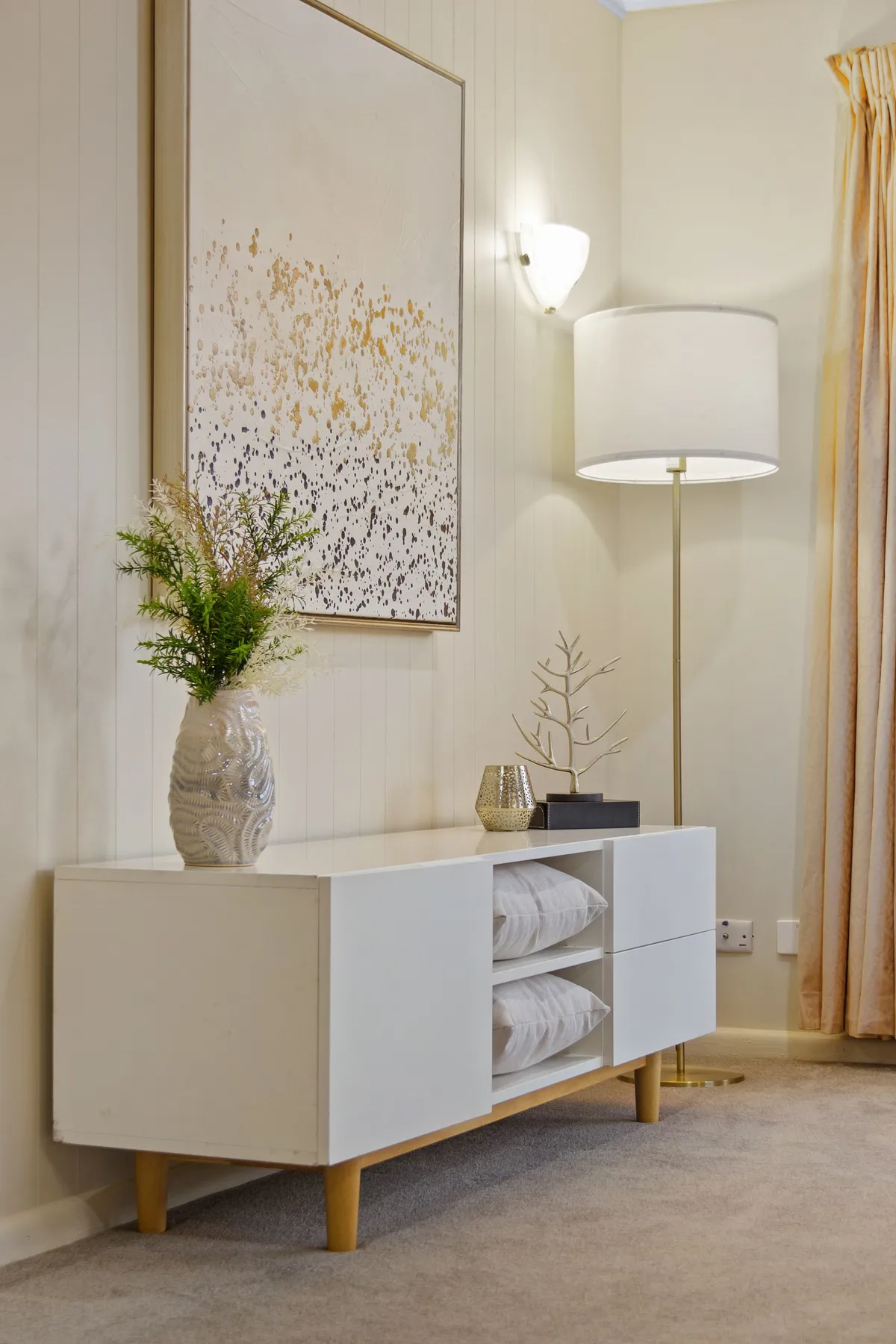 Stylish living room with modern decor, featuring a white sideboard, floor lamp, and abstract art.