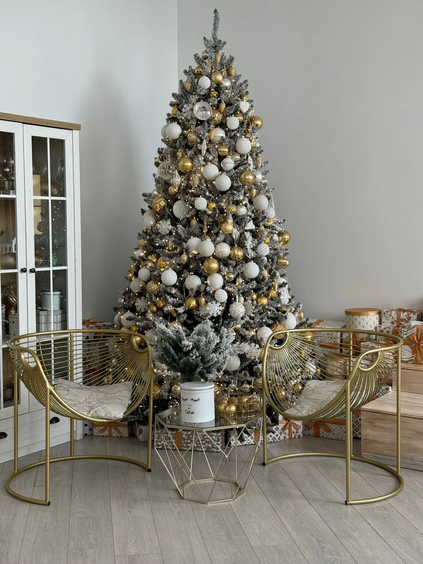 Stylish room featuring a beautifully decorated Christmas tree and elegant golden chairs.