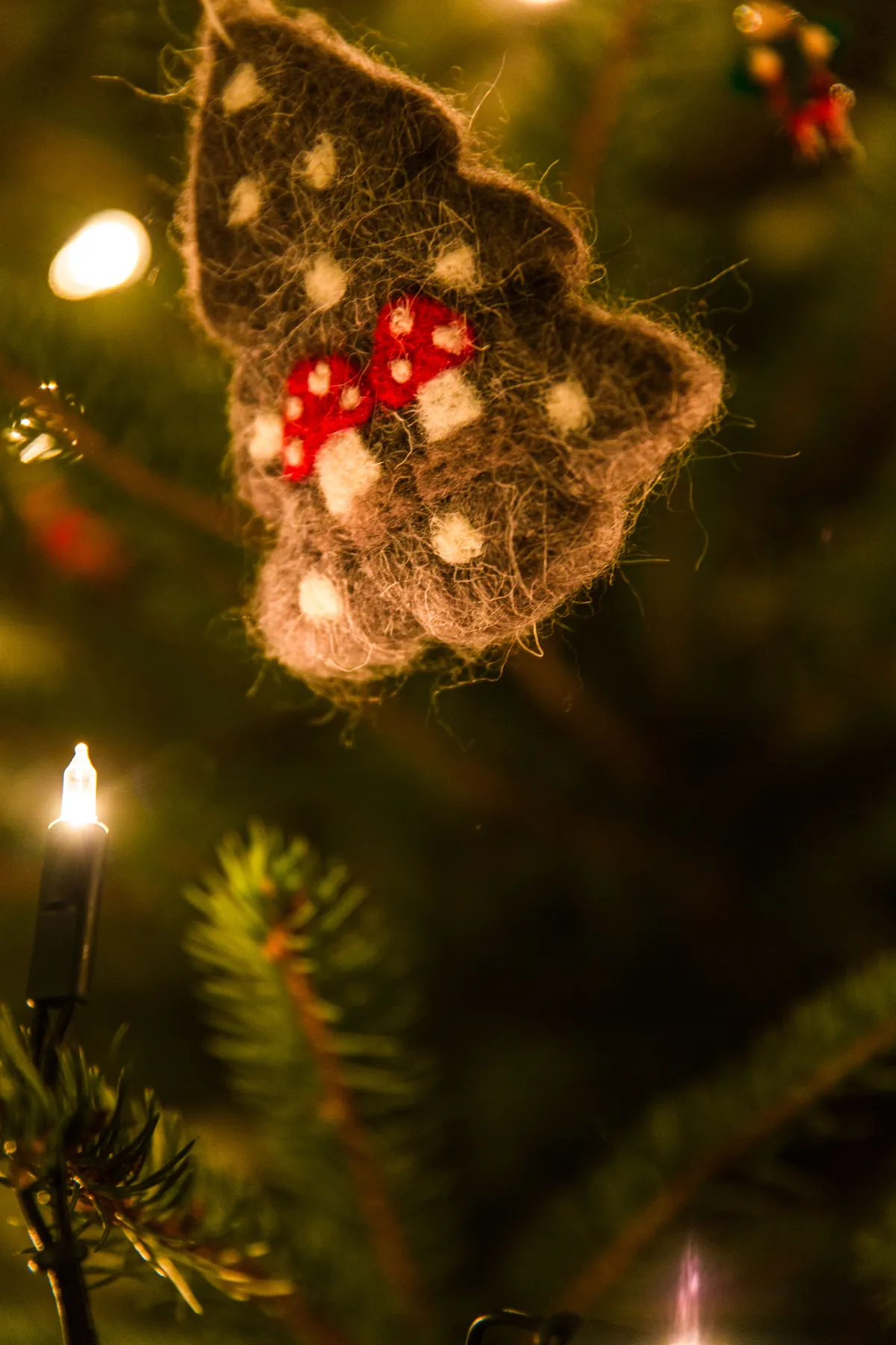 Warm close-up of a handmade Christmas ornament on a brightly lit tree branch.