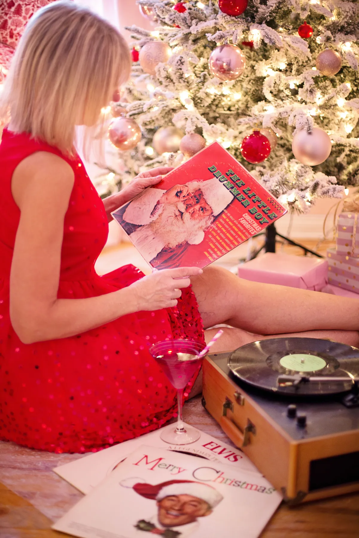 Woman in red dress enjoying vinyl records by a Christmas tree